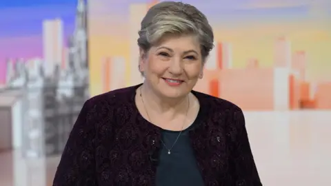 लेबर सांसद एमिली थॉर्नबेरी लाल जैकेट और गहरे रंग का टॉप पहनती हैं।